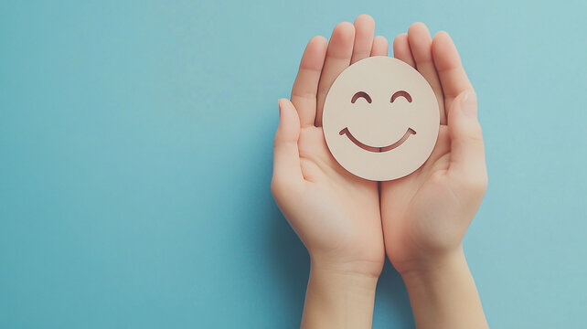 Celebrating World Smile Day with hands holding a cheerful smiley face symbol against a blue backdrop