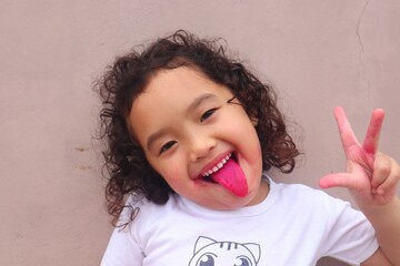 Asian girl sticking out her red tongue with a cute face after eating red dragon fruit.