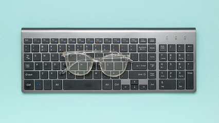 Eyeglasses on Wireless Keyboard Against Pastel Background: Modern Office Essentials