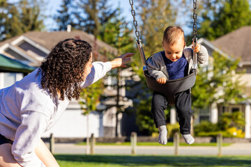Young Child Enjoying a Swing Ride with Adult Supervision in a Sunny Neighborhood Park in Mission, BC, Canada