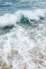 Fototapeta premium Waves crash onto the shore, creating a soothing ambiance and inviting scenery. Perfect for relaxation and beach-themed projects.