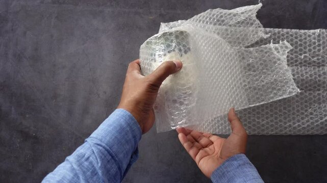 Carefully wrapping hands around an item with bubble wrap to ensure safe shipping and protection