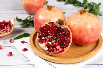 open pomegranates, and pomegranate seeds on wooden table.