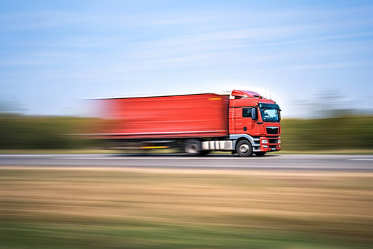 Side profile of a transport truck in motion on a rural road, with the background blurred to emphasize speed and quick transportation services