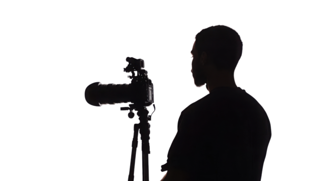 A focused photographer adjusts their camera settings, preparing for a perfect shot in a creative environment. transparent background - Powered by Adobe