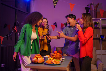 An African American woman and a white woman celebrate with coworkers, drinking, having fun, and smiling together at a lively Halloween night party filled with joy and laughter.