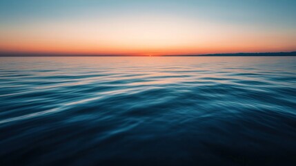 Fototapeta premium Waves gently kiss the shore as the sun sets in peace.