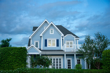 American cottage style house with expensive trees surrounding it.