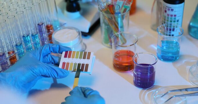 Checking pH level of a liquid using litmus paper in laboratory