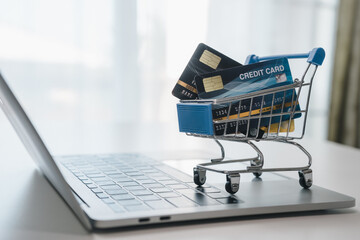 Small shopping cart with credit cards in trolley on laptop, showing a convenient lifestyle in digital purchases with e-commerce at home or anywhere. Online shopping service concept.