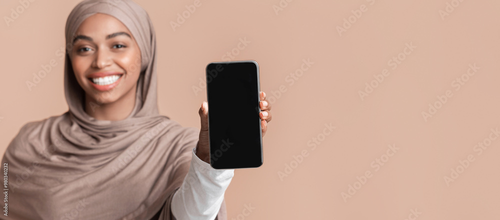 Poster modern smartphone with blank black screen in hand of smiling afro muslim girl in hijab, yellow backg