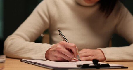 Accountant manager writing on paper with a pen at night in office