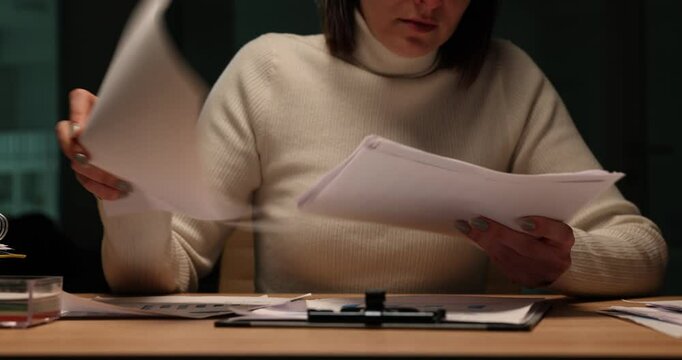 Woman looks through documents late at night in office