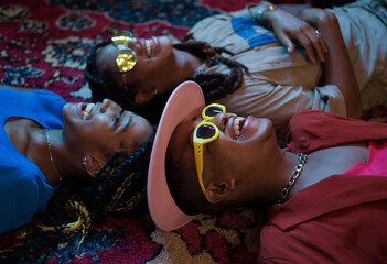 Side view close-up of cool young friends lying in a circle on the floor, each with a smartphone in hand, capturing fun moments together.