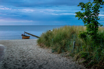 Serene Pathway Leading to the Beach with a Fishing Boat Floating in Calm Waters, Set Against a Beautiful Evening Sky During the Enchanting Blue Hour