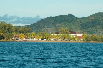 Fototapeta premium As the mountains stand tall in the port, the fishermen's boat sets sail.