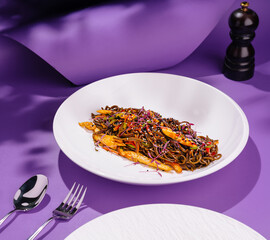Soba noodles with chicken and vegetables on violet background