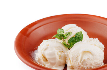 Three scoops of vanilla ice cream melting in rustic bowl with mint garnish