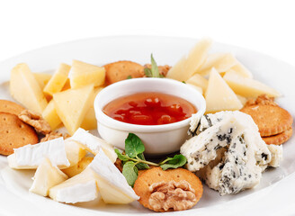 Delicious cheese plate presenting variety of cheeses, nuts, and sauce