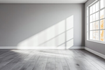 Empty room with natural light streaming through large window, highlighting wooden floors and soft gray walls in a peaceful atmosphere