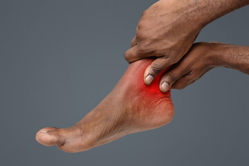 Cropped of african man rubbing his ankle over white background, copy space