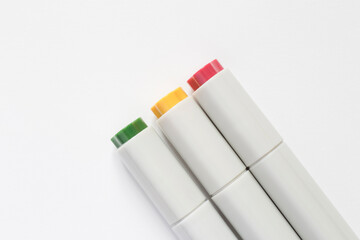 three closed markers lying on white page of sketch book