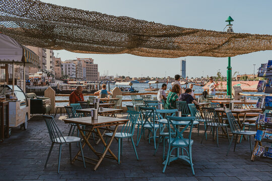 Dubai, UAE - January 6, 2020: Outdoor cafe seating along Dubai Creek with waterfront views