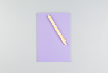 Top view of purple notebook, yellow pen on grey background. School, office wallpaper. Flat lay, copy space.