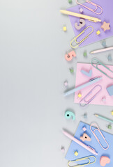 Top view of pink, purple and blue notebooks on grey background. Colorful pens, pencils, paperclips, numbers, shapes and pins. School, office wallpaper. Flat lay, copy space.