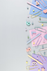 Top view of pink, purple and blue notebooks on grey background. Colorful pens, pencils, paperclips, numbers, shapes and pins. School, office wallpaper. Flat lay, copy space.