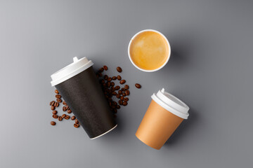 A black coffee cup surrounded by roasted coffee beans on a gray surface