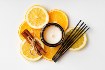 Aromatic arrangement featuring citrus slices and a scented candle on a white surface