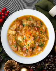 Castilian soup with vegetables, bread croutons and egg. Top view table with Christmas decorations.