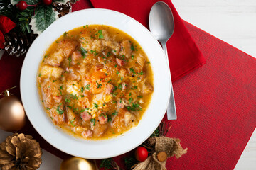 Castilian soup with vegetables, bread croutons and egg. Top view table with Christmas decorations.