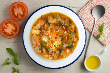 Castilian soup with vegetables, bread croutons and egg. Top view table with  decorations.