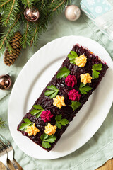 Christmas appetizer New year meal idea. Festive layered salad. Christmas New Year vegetable salad roll with herring and boiled vegetables.