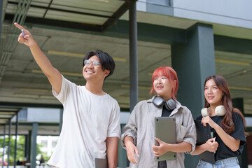 Obraz premium Bright Asian College Student Cheerful people use laptops and tablets to study with a group of classmates. Study outside in a fun way with good friends and social media. Concept of online education.