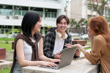 Attractive Asian college students using laptop, tablet, mobile phone to study online social media Finding knowledge together, talking, working as a team. Educational concept success in life.
