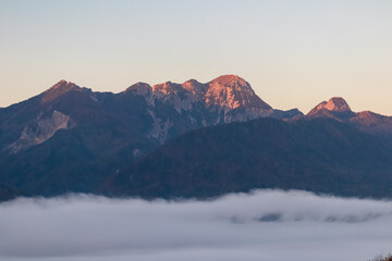 Scenic view of majestic mountain peak Mittagskogel (Kepa) in Karawanks at sunrise seen from Rosental, Carinthia, Austria. Cloud covered alpine landscape. Peaceful scene in Austrian Alps in summer