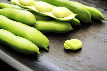 Concept, legumes and nuts as a source of vegetable proteins, fats, vitamins and minerals, green beans and hazelnuts on a dark wooden plate.