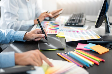 Two creative graphic designer team working on color selection and drawing on graphic tablet, Color swatch samples chart for selection coloring in inspiration to creativity at workplace