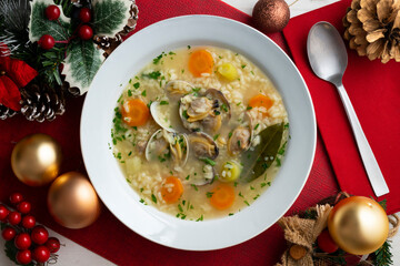 Rice, vegetable and clam soup, traditional Spanish tapa. Top view table with Christmas decorations.