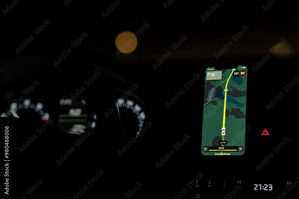 Aufkleber A driver uses a GPS navigation system at night, displaying route information and speed while ensuring a safe journey