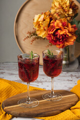 Autumn spiced cocktail with wine on a rustic holiday table. Homemade seasonal drink Sangria for Halloween, Thanksgiving with cinnamon and rosemary. Decorative textile pumpkins and candles