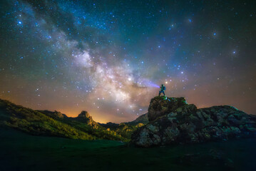 Man contemplates the Milky Way under a starry sky on a rock in Piedrasluengas, Palencia