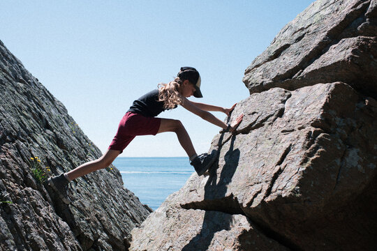girl climbing rocks at the beach in Sk&aring;ne in Sweden