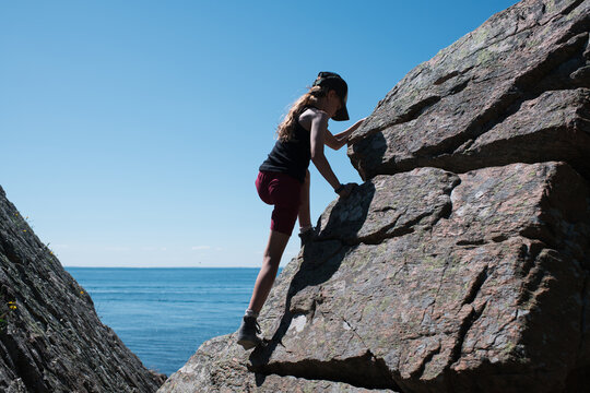 girl climbing the coastline rocks in Sk&aring;ne Sweden in summer