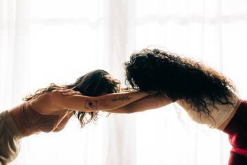 Two women lean forward, in a graceful, supportive gesture