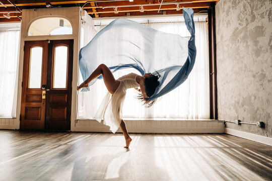 Ballet dancer with flowing blue fabric, performing a graceful movement