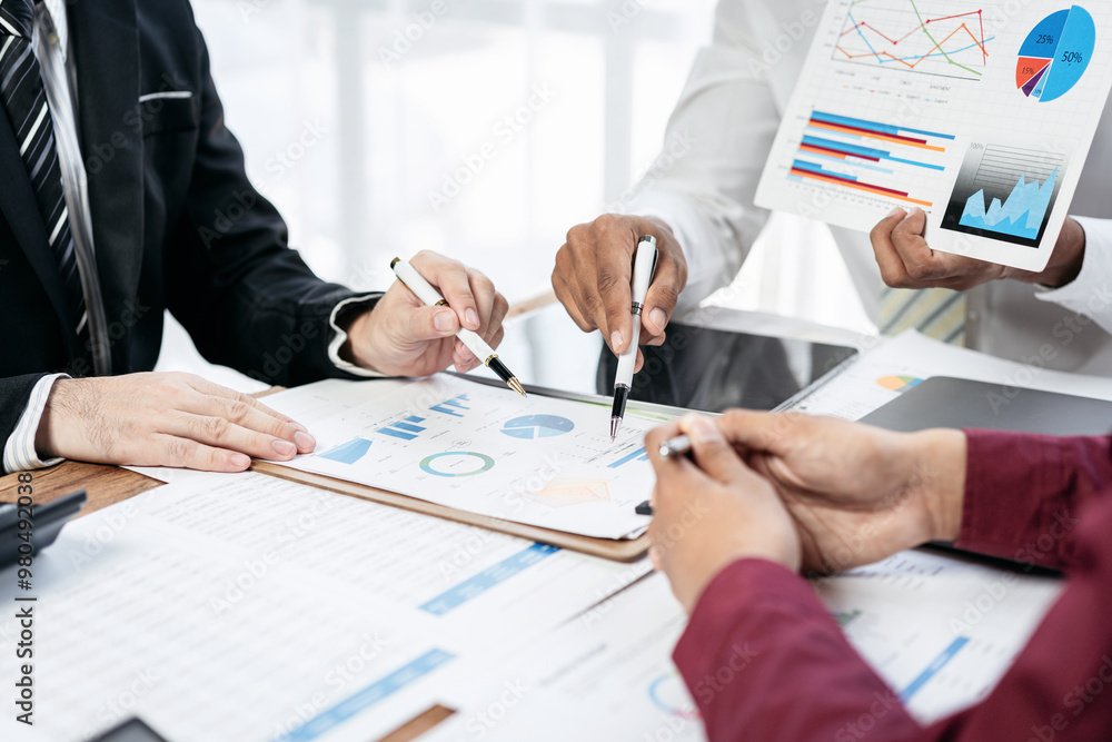 Poster three people are sitting at a table with papers and graphs in front of them
